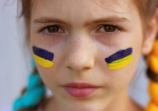 24-73 close-up girl's face with yellow-blue national flags of Ukraine painted on her cheeks. concept of Ukrainian patriotism, independence day. sports and fan support.